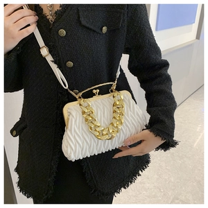 Detail of white pleated cloud bag with chunky gold chain handle on tweed jacket