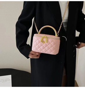 Sac à bandoulière rose matelassé avec fermoir fleur dorée porté sur blazer noir