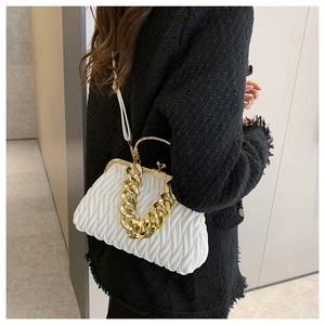 Detail of white matelassé shell bag featuring a gold chain handle and vintage metal clasp