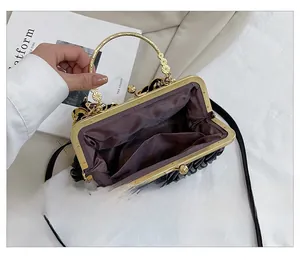 Detail showing the inner lining and golden ball clasp of a black pleated shell bag