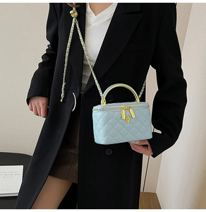Détail macro du mini sac bleu matelassé avec poignée dorée et fermeture à fleur