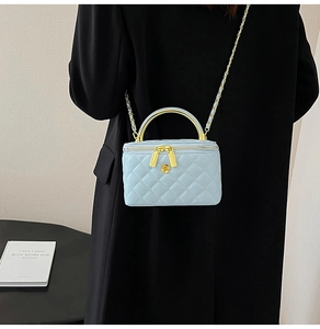 Modèle portant un mini sac matelassé bleu clair avec chaîne et logo floral doré