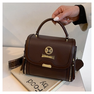 Gros plan du sac en cuir marron avec bandoulière jacquard et logo M doré chic