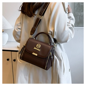 Détail du sac en cuir marron foncé avec large bandoulière et finitions dorées