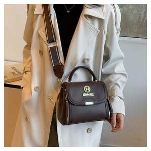 Détail du sac en cuir marron avec logo doré et bandoulière large rayée