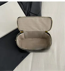 Vue macro de la trousse de maquillage noire matelassée avec fermeture dorée et doublure