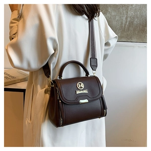 Vue détaillée du sac bandoulière en cuir marron porté sur un trench-coat beige chic
