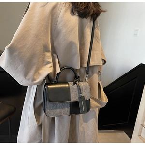 Vue détaillée du sac bandoulière bicolore en tissu gris et finitions en cuir noir