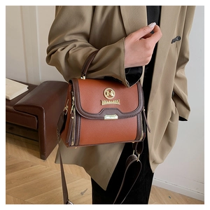 Détail d'un sac cabas en cuir marron avec bandoulière large et accents métalliques dorés