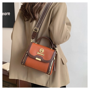 Détail du sac bandoulière en cuir orange avec logo M doré et large sangle en nylon