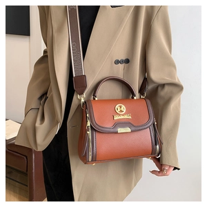 Détail du sac à main orange en cuir grainé avec large bandoulière jacquard