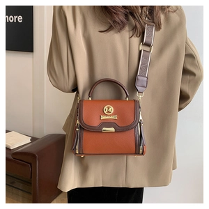 Détail du sac à main en cuir marron avec bandoulière jacquard et logo M doré