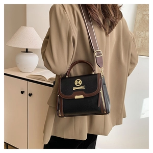 Détail du sac à main en cuir grainé noir avec accents marrons et bandoulière large