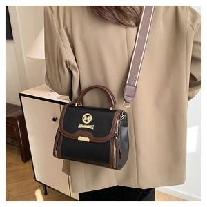 Gros plan du sac bandoulière en cuir avec large sangle et détails dorés sur modèle