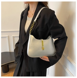 Silver shoulder bag detail with gold chain strap and metallic lock on female model