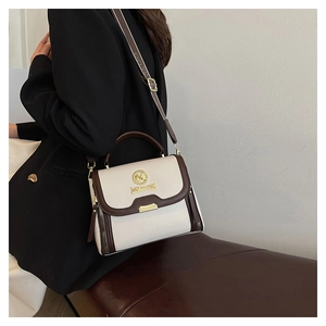 Détail du sac bandoulière bicolore en cuir grainé avec finitions métalliques dorées