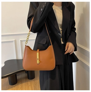 Detail of caramel leather shoulder bag with vintage gold piston clasp and metal chain