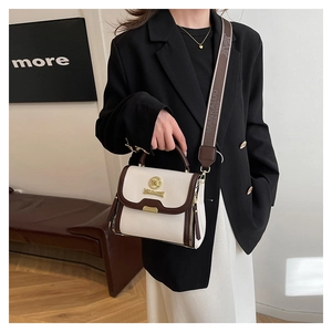 Détail du sac à bandoulière avec sangle large imprimée et plaque logo dorée