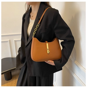 Close-up of caramel leather underarm bag with gold metal clasp and chain detail