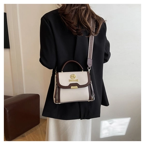 Détail du sac en cuir grainé avec large bandoulière et logo métallique doré