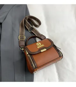 Gros plan du sac en cuir avec logo doré et détail de la large bandoulière imprimée chic