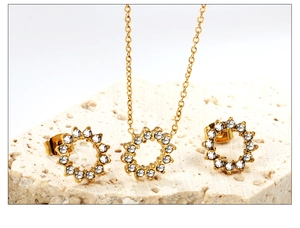 Detail von goldenem Zirkonia-Halsketten-Set und Ohrringen auf strukturiertem Stein