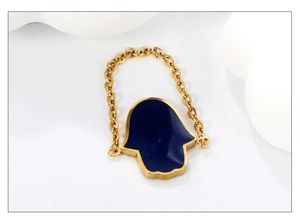 Detail of gold Hamsa hand charm with deep blue enamel inlay on a delicate link chain