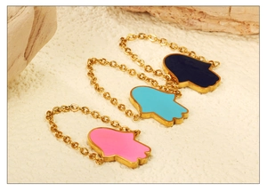 Macro detail of Hamsa hand chain rings with colorful pink and blue enamel dripping oil charms