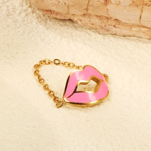 Gold chain ring featuring a pink enamel lip pendant on a natural stone surface