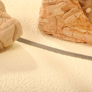 Minimalist silver stainless steel mesh bracelet displayed on natural stone background
