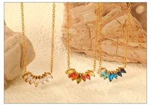 Detailed view of three gold necklaces with marquise-cut gems in various colors