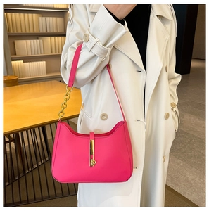 Detail of rose pink crescent bag with golden clasp and chain strap on a white trench coat