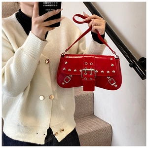 Gros plan d'un sac sous le bras en cuir rouge avec des clous argentés et une boucle