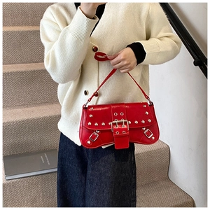 Détail du sac rouge punk chic avec des rivets argentés et une large sangle à boucle