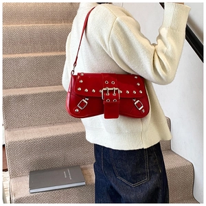 Vue portée du sac à épaule en cuir verni rouge avec rivets punk et détails de boucle