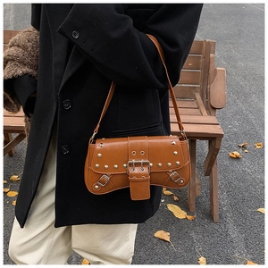 Gros plan d'un sac à bandoulière camel vintage avec clous argentés et boucles en ville