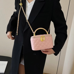 Sac cosmétique matelassé rose avec poignée dorée et bandoulière porté par un mannequin