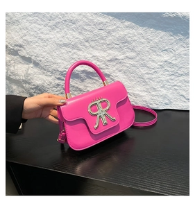 Detail of rose pink mini crossbody bag with silver metal logo and matte leather texture