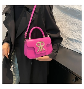 Detail of hot pink crossbody bag with gold logo on black coat for a stylish contrast