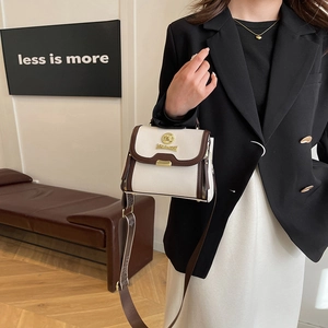 Sac bandoulière beige à large sangle porté par un mannequin en costume chic minimaliste