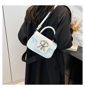 Detail of white leather crossbody bag with gold RR buckle shown on model