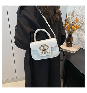 Close-up of white leather handbag featuring a prominent gold metal R logo and top handle