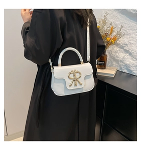 Close-up of cream leather crossbody bag featuring a 3D gold metal R logo and top handle