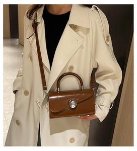 Detail of vintage brown patent leather handbag with glossy finish and metal buckle