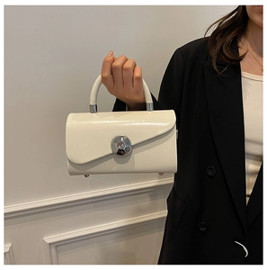Detail of cream box bag with a large silver spherical buckle and stylish top handle