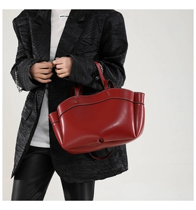 Dettaglio della borsa tote rossa con bordi ondulati e profili neri portata da una modella