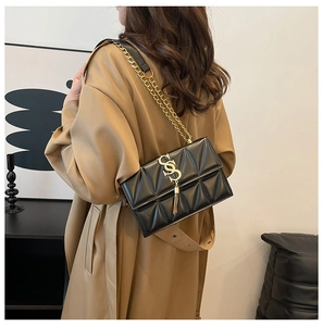 Close-up of black quilted leather shoulder bag with gold chain and tassel detail