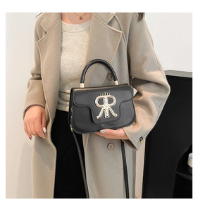 Detail of black leather handbag featuring golden RR crown logo and metallic hardware