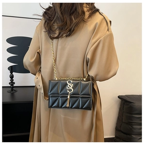 Detailed close-up of a black quilted shoulder bag with gold SS logo and chain tassel