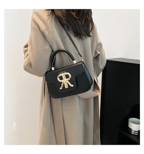 Detail view of black leather mini square bag with gold metal buckle and round handle